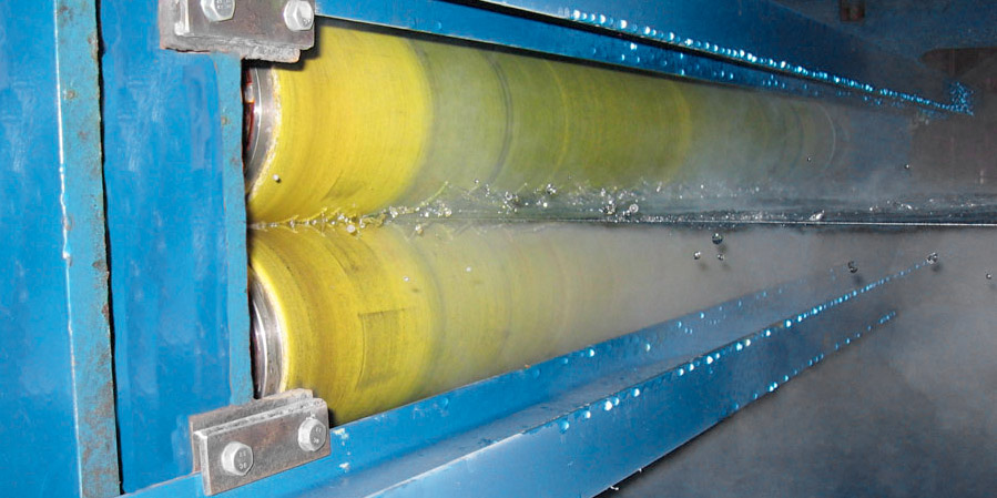 A pair of NCCM<sup>®</sup> Premier Yellow nonwoven rolls wringing fluid from a metal strip.