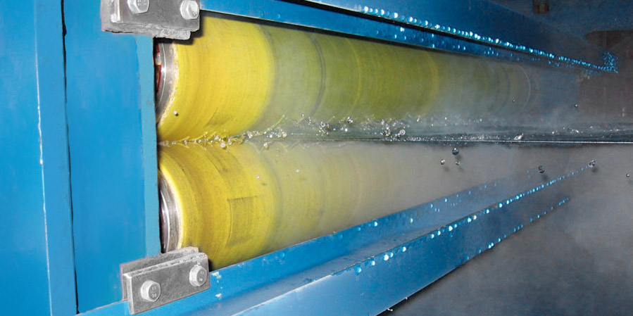 A pair of NCCM<sup>®</sup> Premier Yellow nonwoven rolls wringing fluid from a metal strip.